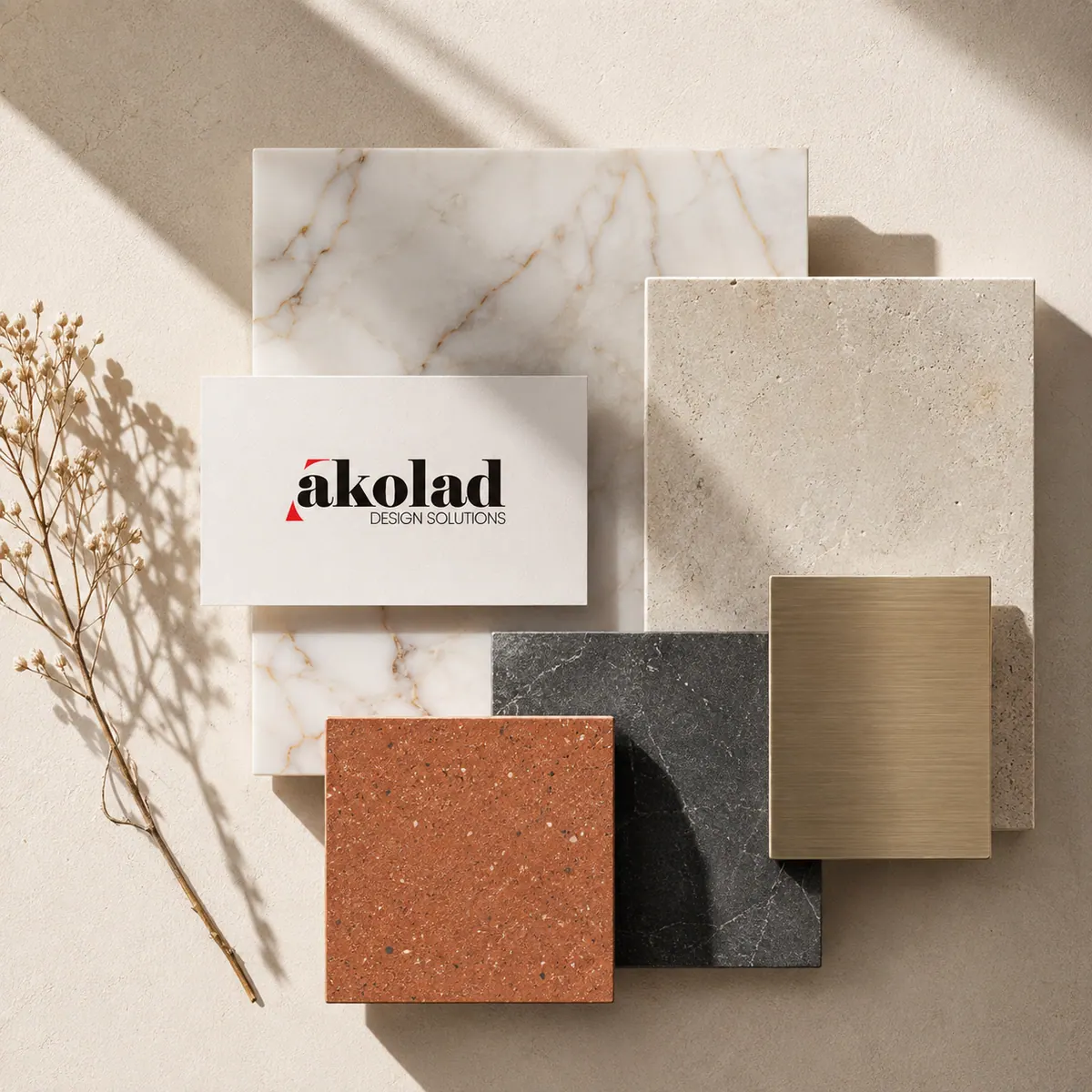 Material samples — marble, travertine, brushed brass and terracotta — arranged with a printed business card.